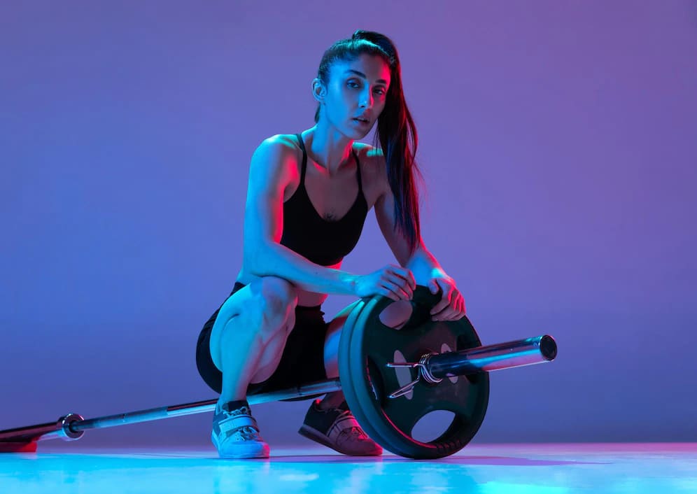 retrato de mulher musculosa treinando com uma barra isolada em fundo roxo em luz neon 155003 45819