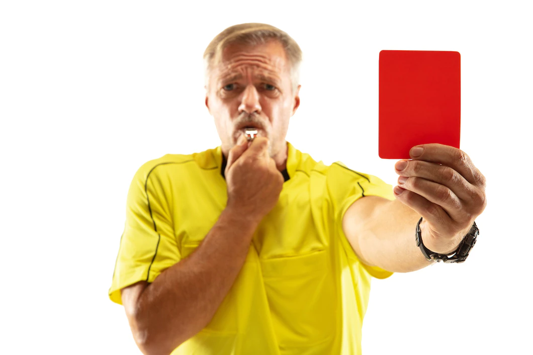 arbitro mostrando um cartao vermelho e gesticulando para um jogador de futebol