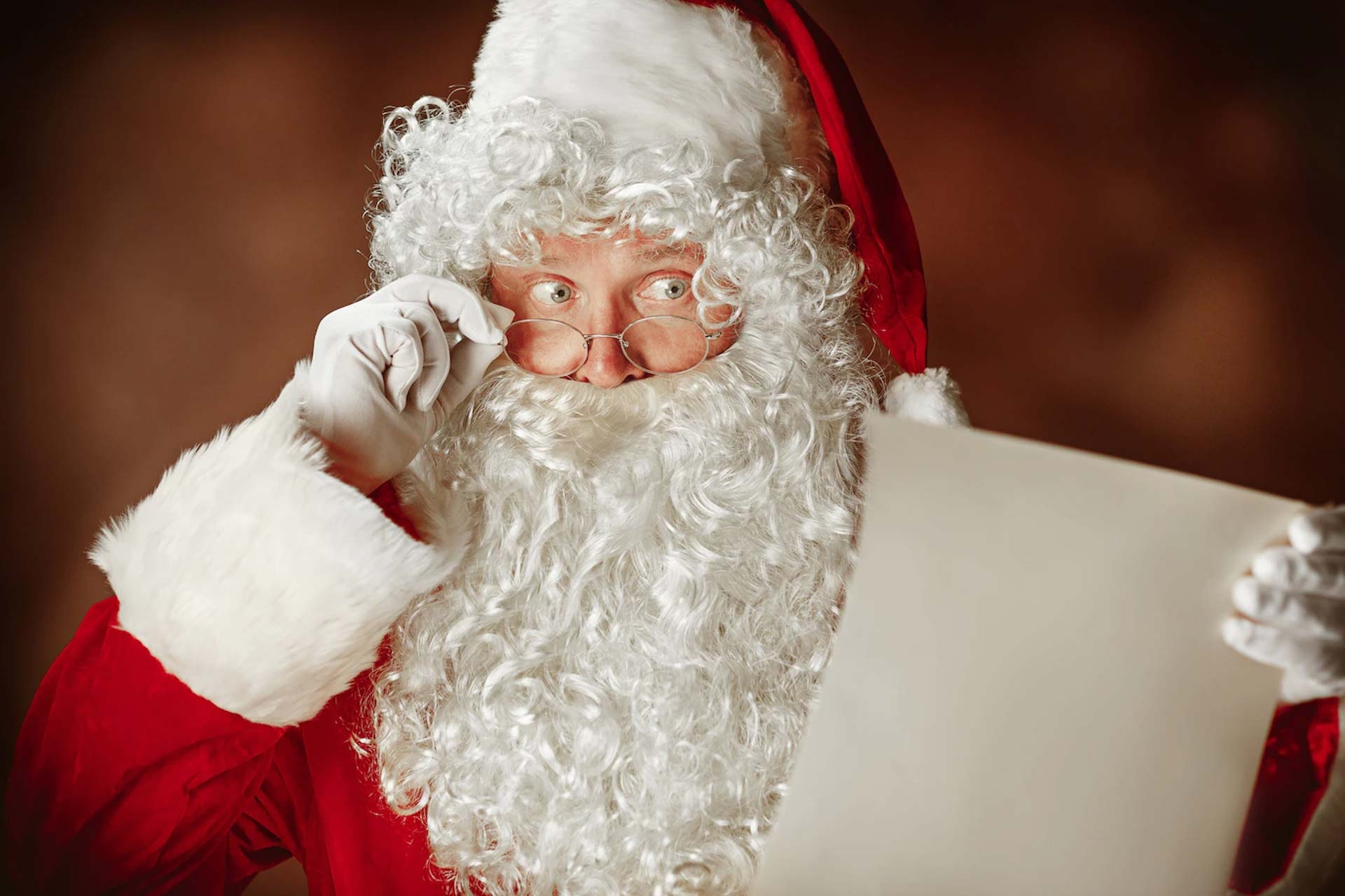 papai noel com uma luxuosa barba branca chapeu de papai noel e uma fantasia vermelha lendo uma carta