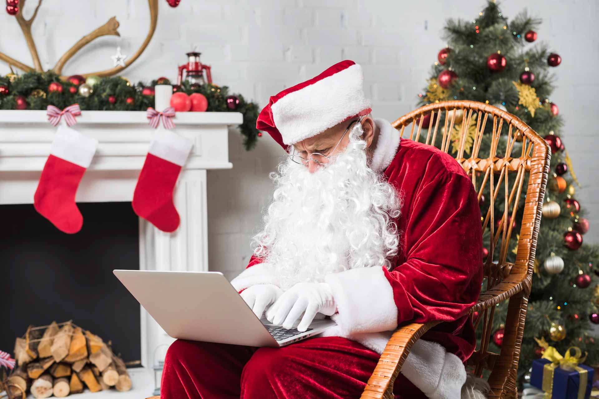 papai noel sentado na cadeira de balanco e digitando no laptop 23 2147949798